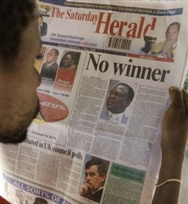 Un zimbabwen lit un journal proche du gouvernement annonant qu'un second tour est ncessaire