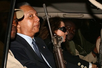 Jean-Claude Duvalier dans une limousine, protg par un garde arm,  son arrive  Port-au-Prince