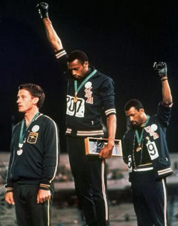 Tommie Smith (au centre) et John Carlos (à droite) levant leurs poings durant les JO de Mexico 1968