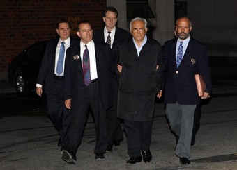 Dominique Strauss-Kahn encadr par des policiers  la sortie du commissariat de Harlem o il tait en garde  vue