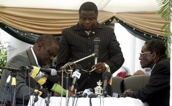 Morgan Tsvangirai signant des documents devant Robert Mugabe le 11 fvrier