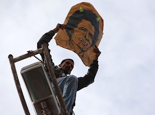 Kadhafi reprsent avec des cornes dans un portrait tenu par un habitant de Benghazi le 23 fvrier 2011