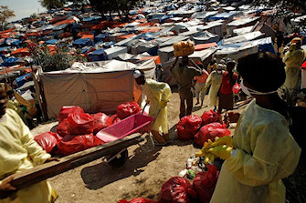 Des travailleurs récoltent des déchets ménagers dans un camp à Port-au-Prince