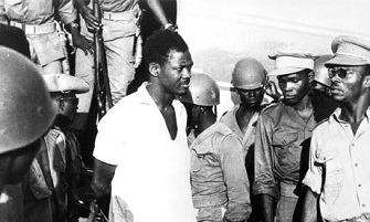 Patrice Lumumba descend d'avion  l'aroport de Leopoldville (2 dcembre 1960) entour de soldats congolais loyaux  Joseph Mobutu